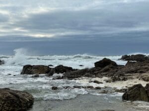 waves crashing on a rocky shore under the cloudy sky